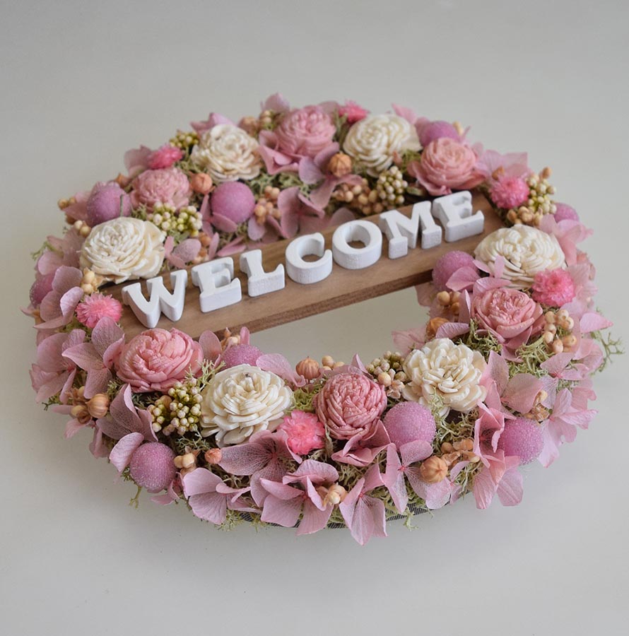 玄関ドアに 白とピンクのお花のかわいらしい色合いのウェルカムリース